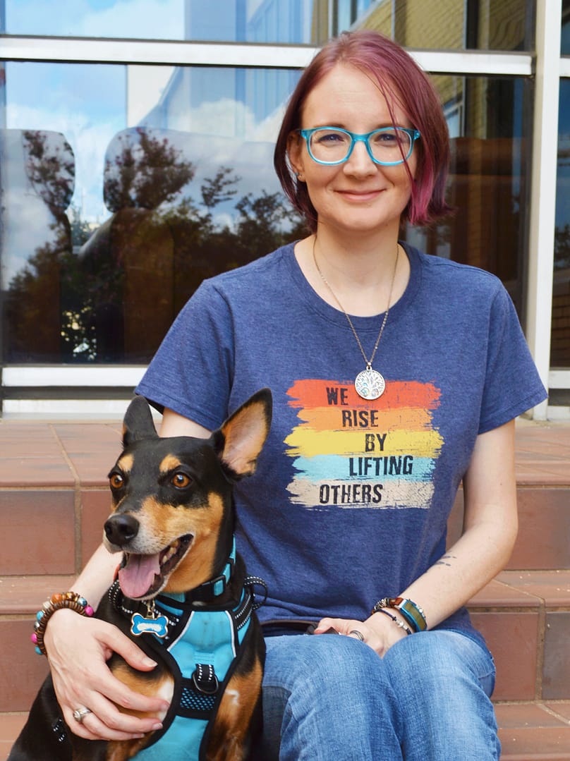Cryss Arkenberg sitting on steps with her arm around her senior dog.