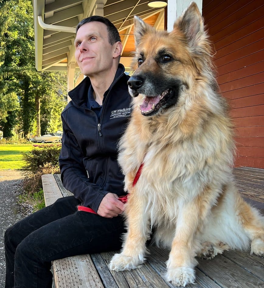 Dr. Matt Kaeberlein sitting with his dog, a large German Shepherd mix.